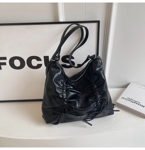 Dettaglio della borsa tote nera in pelle stropicciata con fiocchi e zip in metallo argento