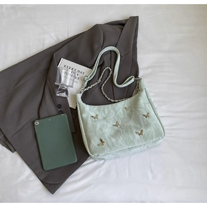 Detail of mint green pleated shoulder bag with golden butterfly charms and chain strap