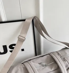 Detalle de la correa de nailon ajustable con hebilla de metal plateado en el bolso informal