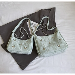 Detail of mint green pleated hobo bag with golden butterfly charm and chain strap