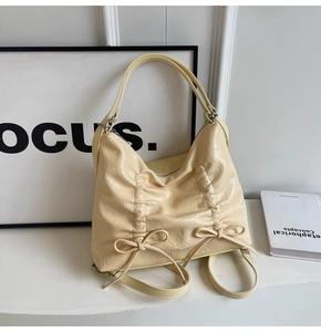 Dettaglio borsa crema in ecopelle plissettata con fiocchi decorativi e finitura lucida