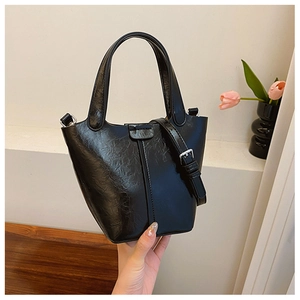 Detail of a black glossy PU leather bucket bag with textured finish and adjustable strap