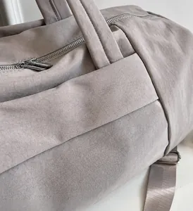 Detalle del bolso de viaje gris impermeable con doble cremallera metálica y correa de nailon