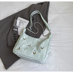 Detail of mint green tote with pleated texture and silver butterfly metal ornaments