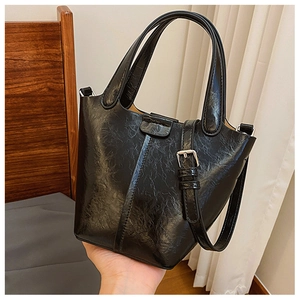 Detail of black glossy wrinkled texture and silver hardware on a mini bucket bag