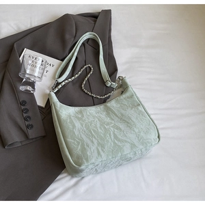 Close-up of mint green pleated hobo bag with silver chain and leather strap detail