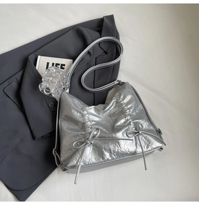Dettaglio della borsa hobo metallizzata argento con trama plissettata e accenti di fiocchi