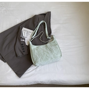 Detail view of mint green crescent bag with metallic crinkled texture and silver chain