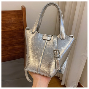 Detail view of silver textured bucket bag with dual handles and metal buckle strap