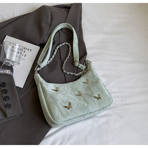 Detail of mint green wrinkled leather bag with silver butterfly charms and chain strap