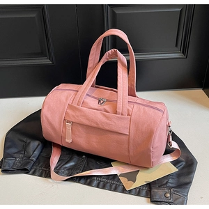 Detalle de un bolso de viaje cilíndrico rosa con textura de nailon y cremalleras metálicas