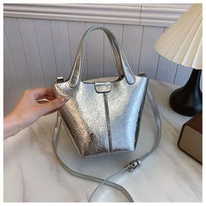 Detailed view of silver metallic bucket bag with crinkled texture and sleek top handle