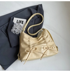 Dettaglio borsa hobo beige con texture in pelle plissettata e fiocchi decorativi laterali