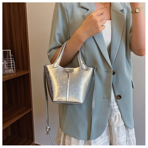 Detail of silver metallic bucket bag with dual handles and smooth textured surface