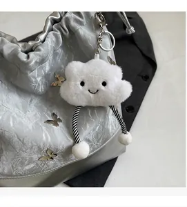 Detalle de colgante de nube de felpa blanca con patas a rayas en bolso plateado