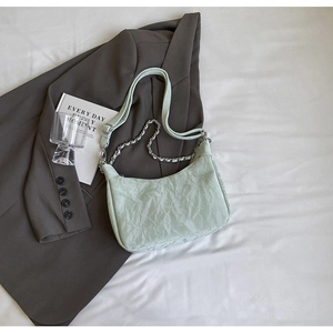 Detail of mint green crescent bag with pleated texture and silver chain strap