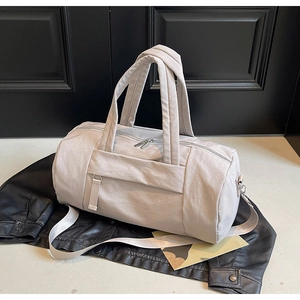 Vista superior de bolsa de viaje beige sobre chaqueta de cuero mostrando tejido nylon