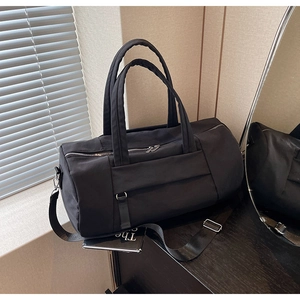 Detalle de una bolsa de viaje negra de gran capacidad con asas y doble cremallera
