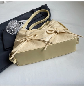 Dettaglio della trama in pelle plissettata e dei fiocchi su una borsa a spalla beige