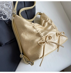 Dettaglio della borsa in pelle plissettata crema con fiocchi e logo del marchio
