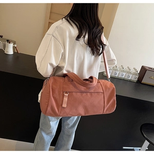 Mujer llevando bolso de viaje grande de lona terracota con correa ajustable
