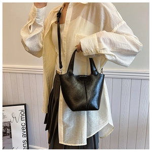 Detailed view of a black bucket bag in glossy faux leather with removable shoulder strap