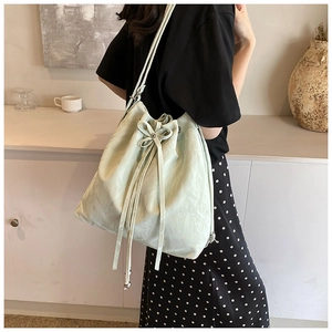 Close-up of mint green drawstring bucket bag with pleated texture and bow detail