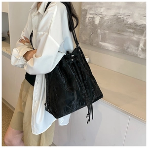 Detail of black drawstring bucket bag showing shiny wrinkled texture and silver accents