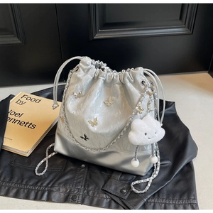 Detail van zilveren emmerzak met vlinderdecoratie en wolkenhanger op leer gestyled