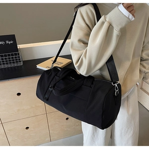Vista lateral de bolsa deportiva cilíndrica negra con correas de nailon sobre modelo