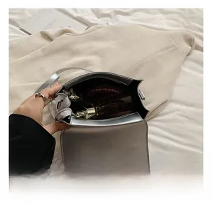 Détail de l'intérieur du sac bandoulière argenté avec compartiment principal et poche zippée