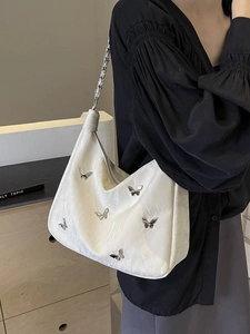 Chic beige pleated tote bag with silver butterfly charms and chain strap on a model