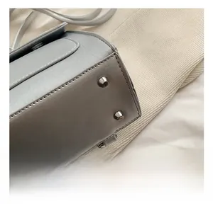 Détail des pieds de protection en métal argenté et du cuir gris au bas du sac