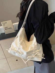 Borsa a tracolla beige plissettata con fiocchi indossata da modella in ambiente moderno