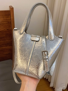 Silver metallic textured bucket bag with minimalist fold closure and crossbody strap