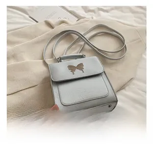 Détail macro du sac à main en cuir argenté avec fermoir papillon et poignée lisse