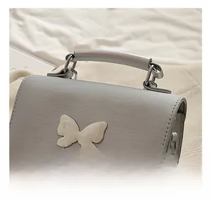 Gros plan d'un sac à main gris clair en cuir synthétique avec un fermoir papillon en métal
