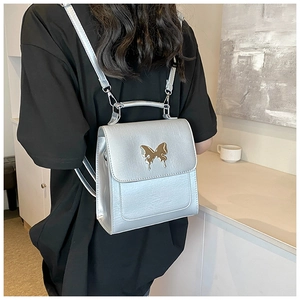 Gros plan du mini sac à dos argenté avec une boucle papillon dorée et texture délicate