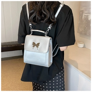 Détail d'un mini sac à dos argenté métallisé avec une boucle papillon dorée décorative