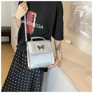 Modèle avec sac à main argenté en cuir grainé et fermoir papillon doré élégant
