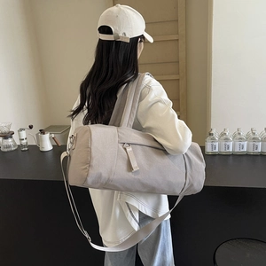 Bolso de viaje gris de gran capacidad con correa mostrado por una modelo en un café