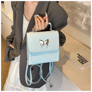 Détail d'un sac à dos carré bleu clair avec relief papillon argenté en similicuir lisse