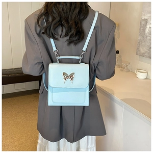 Vue arrière d'un mannequin portant le mini sac à dos bleu clair avec boucle papillon argent