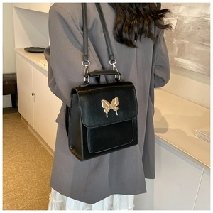 Détail d'un sac à dos vintage noir avec une boucle papillon en métal doré liquide