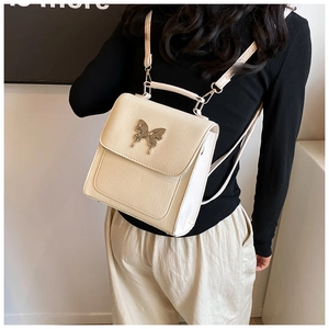 Modèle portant un sac à dos en cuir grainé crème avec fermoir papillon argenté