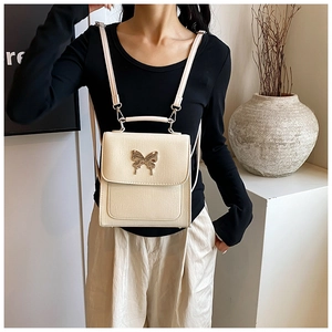 Détail du sac à dos beige en cuir texturé avec un fermoir papillon en métal doré