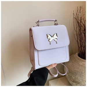 Détails d'un sac à dos violet en cuir avec un ornement papillon en métal argenté