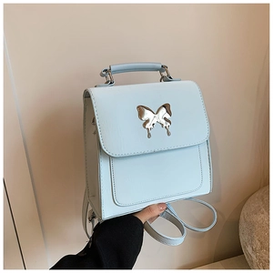 Détail du sac à dos en cuir bleu clair avec boucle papillon argentée et poignée