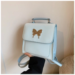 Détail d'un mini sac à dos bleu clair en cuir avec fermoir papillon doré élégant