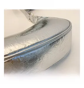 Détail d'un sac argenté métallisé avec texture froissée et gravure du logo Casheramera